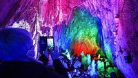 Seorang pengunjung mengabadikan warna-warni Gua Dechen dengan ponselnya.