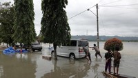 Sejumlah warga mendorong mobil yang terjebak banjir.