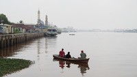 Tiga warga memancing di Sungai Kapuas yang diselimuti kabut asap di Pontianak, Kalimantan Barat.