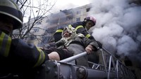 Tak hanya menghancurkan sejumlah kendaraan, serangan yang terjadi di Kyiv, Ukraina, juga turut menyebabkan kebakaran di sebuah gedung apartemen di kawasan tersebut. Dalam gambar milik Layanan Darurat Negara Ukraina, petugas pemadam kebakaran mengevakuasi seorang wanita tua dari gedung apartemen yang terdampak serangan di Kyiv. Servicio Estatal de Emergencia de Ucrania vía AP.