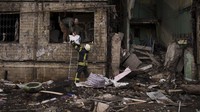 Petugas pemadam kebakaran Ukraina membantu seorang pria mengeluarkan barang-barang dari bangunan yang hancur setelah terkena tembakan artileri di Kyiv, Ukraina, Senin (14/3/2022) waktu setempat. AP Photo/Felipe Dana.