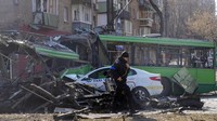 Seorang tentara Ukraina melintas di depan bus dan taksi yang hancur akibat serangan udara Rusia di Kyiv, ibu kota Ukraina, Senin (14/3/2022) waktu setempat. AP Photo/Efrem Lukatsky.