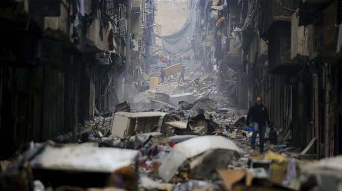 FILE - Residents walk through the destruction of the once rebel-held Salaheddine neighborhood in the eastern Aleppo, Syria, Friday, Jan. 20, 2017. Tuesday, March 15, 2022 marks the 11th anniversary of Syria's revolution-turned-civil war. This year, many survivors are watching in shock as Ukrainians face the same horrors they did. (AP Photo/Hassan Ammar, File)