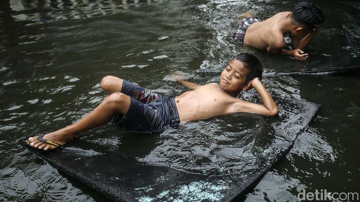 Banjir di Duren Sawit, Jakarta Timur, telah terjadi hampir sepekan. Banjir ini jadi tempat bermain anak-anak.