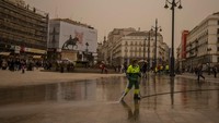 Orang-orang sibuk membersihkan debu di jalan dan permukiman di Madrid pada Selasa (15/3/2022). (AP/Manu Fernandez) 