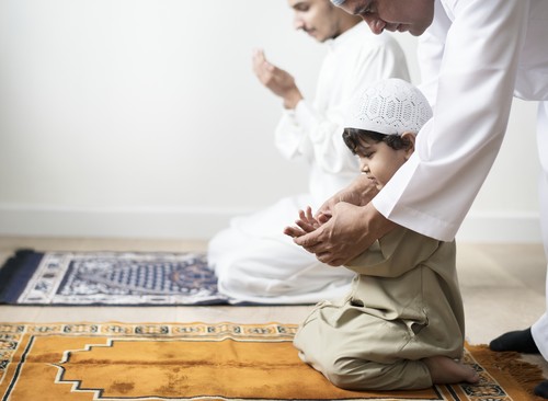 Muslim boy learning how to make Dua to Allah
