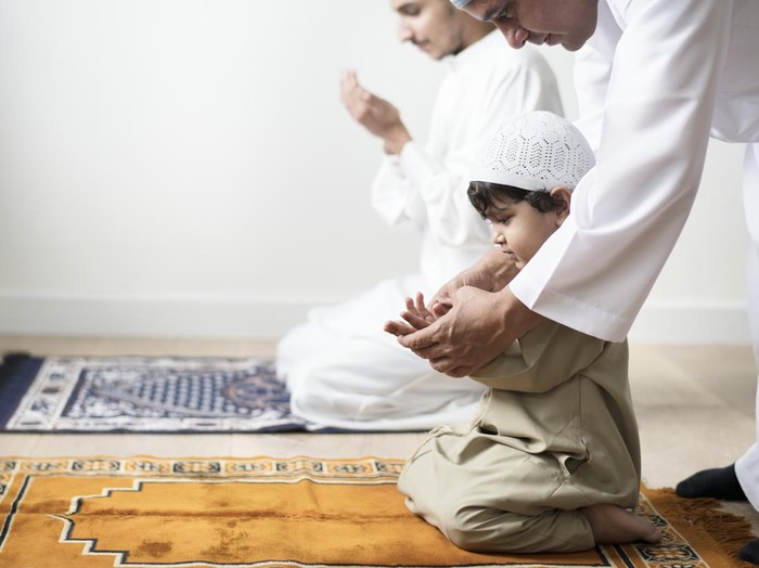 Muslim boy learning how to make Dua to Allah