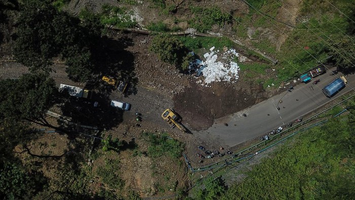 Petugas mengoperasikan alat berat saat perbaikan jalan amblas jalur Bandung-Cirebon di Tomo, Kabupaten Sumedang, Jawa Barat, Rabu (16/3/2022). Tingginya intensitas hujan serta labilnya tanah di kawasan tersebut membuat jalan nasional yang menghubungkan Kota Bandung dan Cirebon amblas sekitar satu meter dengan panjang 60 meter. ANTARA FOTO/Raisan Al Farisi/tom.