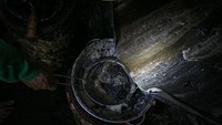Pekerja menyaring minyak goreng yang dihasilkan dari mesin penyuling biji kapuk randu. 2 ton biji kapuk randu bisa menghasilkan sekitar 200 liter minyak goreng setiap hari. 
