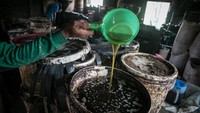 Pekerja memindahkan minyak goreng yang dihasilkan dari biji kapuk randu. Minyak goreng dari penyulingan biji kapuk ini untuk dikirim ke Jakarta, Magelang dan Semarang.
