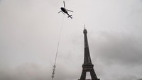 Puncak Menara Eiffel bertambah 6 meter usai diberi menara telekomunikasi. Sebuah helikopter membawa material ke puncak menara.