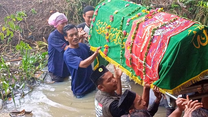 Warga Perumahan Mutiara Indah 2, Serang, membawa jenazah seberangi sungai imbas jembatan putus pascaluapan Sungai Cibanten.