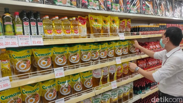 Karyawan toserba sedang merapihkan minyak goreng kemasan.