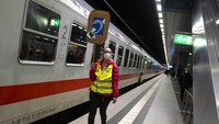 Sukarelawan membawa tanda untuk membantu kaum difabel di salah satu peron di Stasiun Berlin, Selasa (15/3/2022).  Relawan siap membantu para pengungsi Ukraina yang baru tiba. (AP/Markus Schreiber)