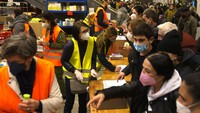 Pengungsi dari Ukraina mendapatkan barang bantuan dari relawan setelah mereka tiba di stasiun kereta api utama di Berlin, Jerman. Sukarelawan dengan rompi kuning dan oranye menawarkan segalanya mulai dari sampo hingga pengisi daya ponsel. (AP/Markus Schreiber)