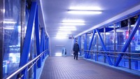 Seorang pria berjalan dengan membawa makanan di jembatan penyeberangan di Causeway Bay, sebuah distrik perbelanjaan terkenal di Hong Kong yang kini tampak sepi.