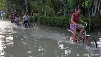 Warga dengan sepeda menerobos banjir di Desa Butuh, Purworejo, Jawa Tengah, Kamis (17/3/2022).