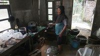 Seorang warga memasak lauk untuk korban banjir di dapur umum yang juga terendam banjir.