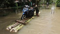 Warga mengevakuasi kendaraan bermotor menggunakan rakit darurat akibat banjir di Desa Nusadadi, Sumpiuh, Banyumas.