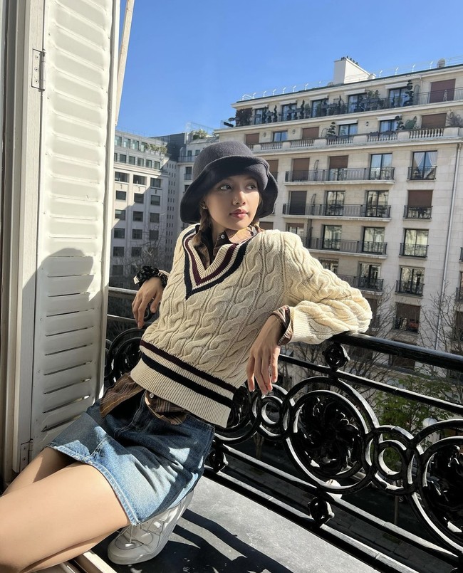 Lisa BLACKPINK memamerkan outfitnya saat berjemur di pagi hari dan bersantai di balkon. Penampilannya terlihat kasual memakai knit sweater krem dan rok denim pendek dengan topi berwarna hitam. Foto: dok. Instagram @lalalalisa_m