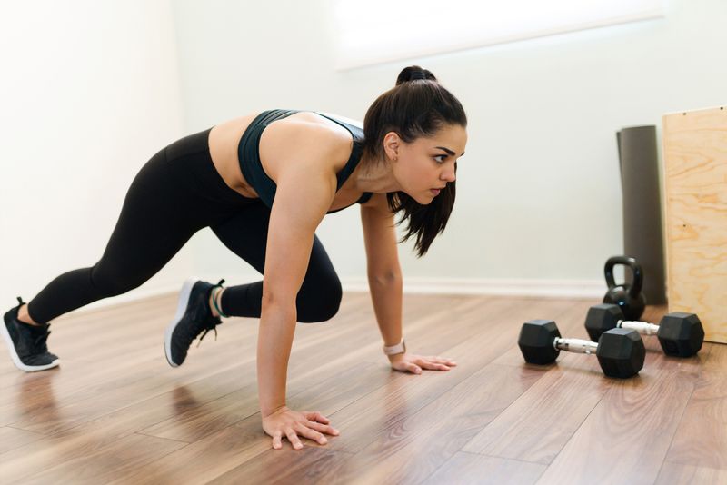 Olahraga mengecilkan perut Exercising at home with a high intensity interval training program. Fitness woman doing mountain climbers and cardio workout