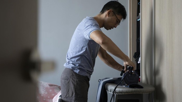 Asian adult man help out in household chores while working from home in Singapore residential
