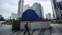 Warga melintas di depan Tugu Sepeda di Jalan Sudirman, Jakarta, Jumat (18/3/2022).