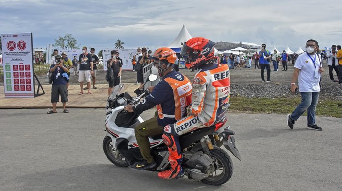 Pembalap Repsol Honda Team Marc Marquez membonceng marshal usai terjatuh saat kualifikasi MotoGP di Pertamina Mandalika International Street Circuit, Praya, Lombok Tengah, NTB, Sabtu (19/3/2022). Pembalap Monster Energy Yamaha Fabio Quartararo merebut pole position dan berhak start terdepan pada balapan MotoGP seri kedua 2022 pada Minggu (20/3) setelah mencatatkan waktu tercepat 1 menit 31,067 detik.ANTARA FOTO/Ahmad Subaidi/rwa.