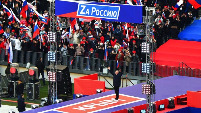 Russian President Vladimir Putin waves to people gathered to attend the concert marking the eighth anniversary of the referendum on the state status of Crimea and Sevastopol and its reunification with Russia, in Moscow, Russia, Friday, March 18, 2022. (Evgeny Biyatov/Sputnik Pool Photo via AP)