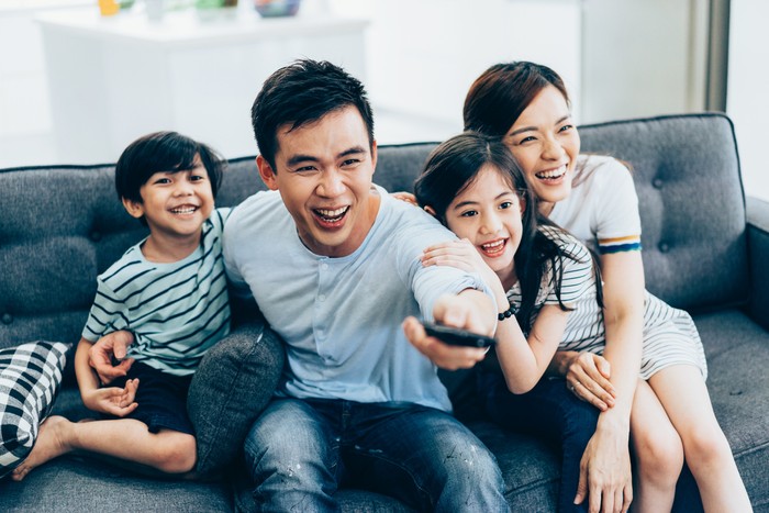 Cheerful asian family relaxing at home watching tv