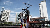 Seorang pesepeda berfoto dengan mengangkat sepedanya di JPO Pinisi.