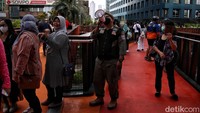 Petugas Satpol PP DKI dengan pengeras suara mengingatkan warga untuk tetap memperhatikan protokol kesehatan.