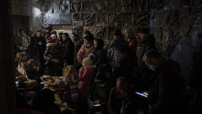 People gather in a basement, used as a bomb shelter, during an air raid in Lviv, Western Ukraine, Saturday, March 19, 2022. Lviv has been a refuge since the war began nearly a month ago, the last outpost before Poland and host to hundreds of thousands of Ukrainians streaming through or staying on. (AP Photo/Bernat Armangue)