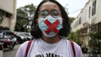 Sejumlah orang yang mendampingi Haris Azhar tampak mengenakan masker dengan simbol tanda silang merah.
