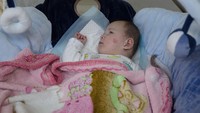 Seorang bayi terbaring di tempat tidur yang berada di ruang bawah tanah sebuah gedung di Kyiv, Ukraina, Minggu (20/3/2022).