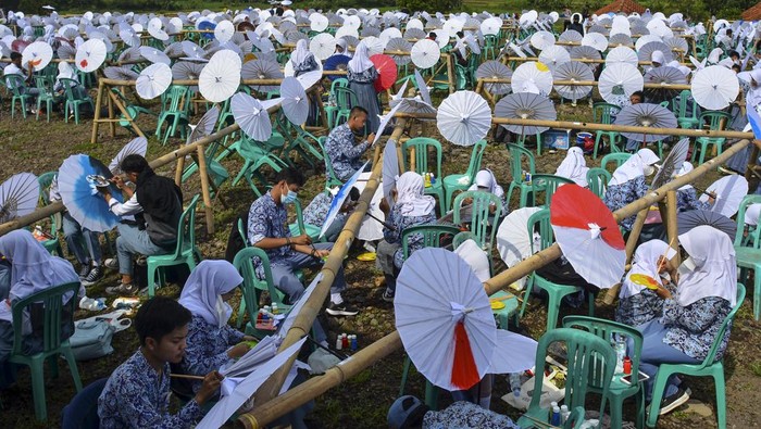 Sejumlah siswa melukis payung geulis pada Festival, Lomba dan Rekor Melukis 2022 Payung Geulis Se-Jawa Barat di SMA Negeri 10 Kota Tasikmalaya, Jawa Barat, Sabtu (19/3/2022). Festival melukis payung geulis yang merupakan Warisan Budaya Takbenda (WBTb) itu memecahkan rekor MURI dengan diikuti sebanyak 2022 peserta secara langsung dan daring. ANTARA FOTO/Adeng Bustomi/rwa.