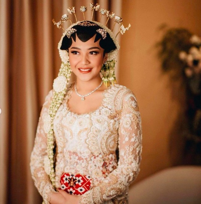 Putri tampaknya tidak ingin mengubah fitur wajahnya dengan riasan. Sang makeup artist mengaksentuasi bagian-bagian yang wajah perlu dipertegas. Untuk riasan bibir pada akad  nikah, Putri tampil dengan lipstik bernuansa coral. Foto: dok. Morden.co