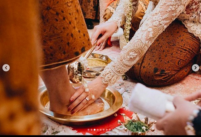 Ranupada menjadi tahapan selanjutnya dalam prosesi panggih ini. Guinandra menginjak telur dengan kaki, lalu Putri membasuh kaki suaminya dengan air bersih (wiji dadi) sebagai wujud bakti istri kepada suami agar rumah tangga bahagia dan harmonis. Guinandra lalu membantu Putri bangkit berdiri, yang dimaknai kedudukan yang setara keduanya. Duduk sama rendah, berdiri sama tinggi. (Foto: Dok. Morden)