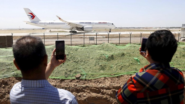 FILE - Residents watch as a China Eastern passenger jet prepares to take off on a test flight from the new Beijing Daxing International Airport on Monday, May 13, 2019. State media are reporting a Chinese airliner from China Eastern with 133 people on board crashed in the southern province of Guangxi on Monday, sparking a mountainside fire. (AP Photo/Ng Han Guan, File)