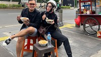 Foto saat Gilang dan Shandy makan bubur di pinggir jalan ini sempat menuai kontroversi. Banyak netizen yang menyoroti outfit mewah yang mereka kenakan. Makan bubur saja pakai item fashion mahal.  Foto: Instagram @juragan_99