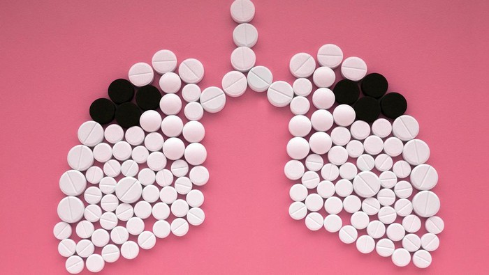 Lungs made of white and black pills on pink background. World Tuberculosis Day concept