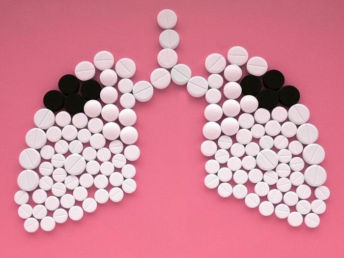 Lungs made of white and black pills on pink background. World Tuberculosis Day concept