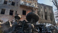 Sebuah mobil hancur terlihat di depan gedung yang rusak akibat penembakan di Kharkiv, Ukraina, Selasa, (15/3/2022). (AP Photo/Andrew Marienko)