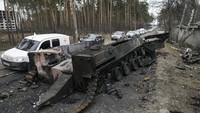 Mobil melewati tank Rusia yang hancur saat konvoi kendaraan yang mengevakuasi warga sipil meninggalkan Irpin, di pinggiran Kyiv, Ukraina, (9/3/2022). (AP Photo/Vadim Ghirda)
