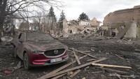 Sebuah mobil yang terbakar berdiri di samping sisa-sisa rumah budaya setempat menyusul serangan udara malam di desa Byshiv, 40 kilometer barat Kyiv, Ukraina, Jumat, (4/3/2022). (AP/Efrem Lukatsky)
