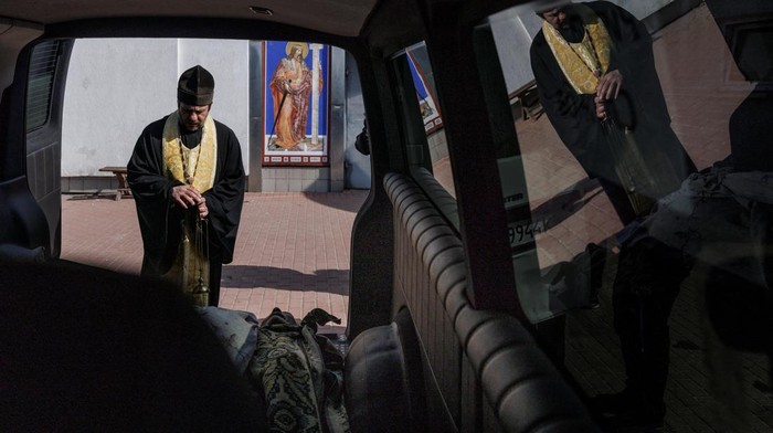 SENSITIVE MATERIAL. THIS IMAGE MAY OFFEND OR DISTURB    A priest blesses the bodies of unidentified people at a crematorium, who were killed during Russia's attack on Ukraine and were picked up by a volunteer from Hostomel, in Kyiv, Ukraine, March 20, 2022. REUTERS/Thomas Peter