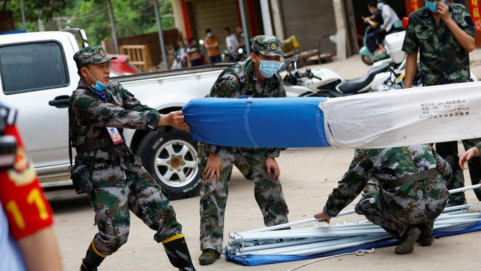 Warga China Datangi Lokasi Pesawat Jatuh People stand behind a security cordon at the entrance of Lu village near the site where a China Eastern Airlines Boeing 737-800 plane flying from Kunming to Guangzhou crashed, in Wuzhou, Guangxi Zhuang Autonomous Region, China March 22, 2022. REUTERS/Carlos Garcia Rawlins