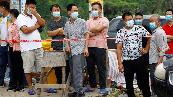People stand behind a security cordon at the entrance of Lu village near the site where a China Eastern Airlines Boeing 737-800 plane flying from Kunming to Guangzhou crashed, in Wuzhou, Guangxi Zhuang Autonomous Region, China March 22, 2022. REUTERS/Carlos Garcia Rawlins