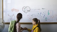 Dua anak pengungsi dari Ukraina berdiri di depan papan tulis sebelum kelas mereka dimulai di Berlin, Jerman, Senin (21/3/2022).  