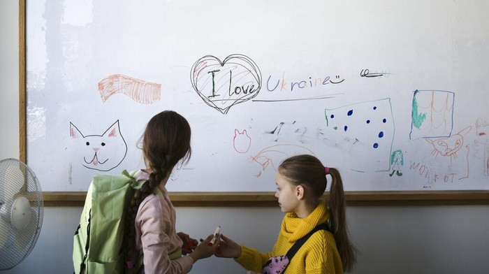 Anak-anak Pengungsi Ukraina Mulai Sekolah di Jerman Two refugee children from the Ukraine stand in front of a white board before their classes start in Berlin, Germany, Monday, March 21, 2022. Forty Ukrainian refugee children started their first day of elementary school in Berlin on Monday only weeks after they fled the war back home. The two private refugee classes were put together by two Berlin volunteers who managed to raise funds, get free class rooms. (AP Photo/Markus Schreiber)